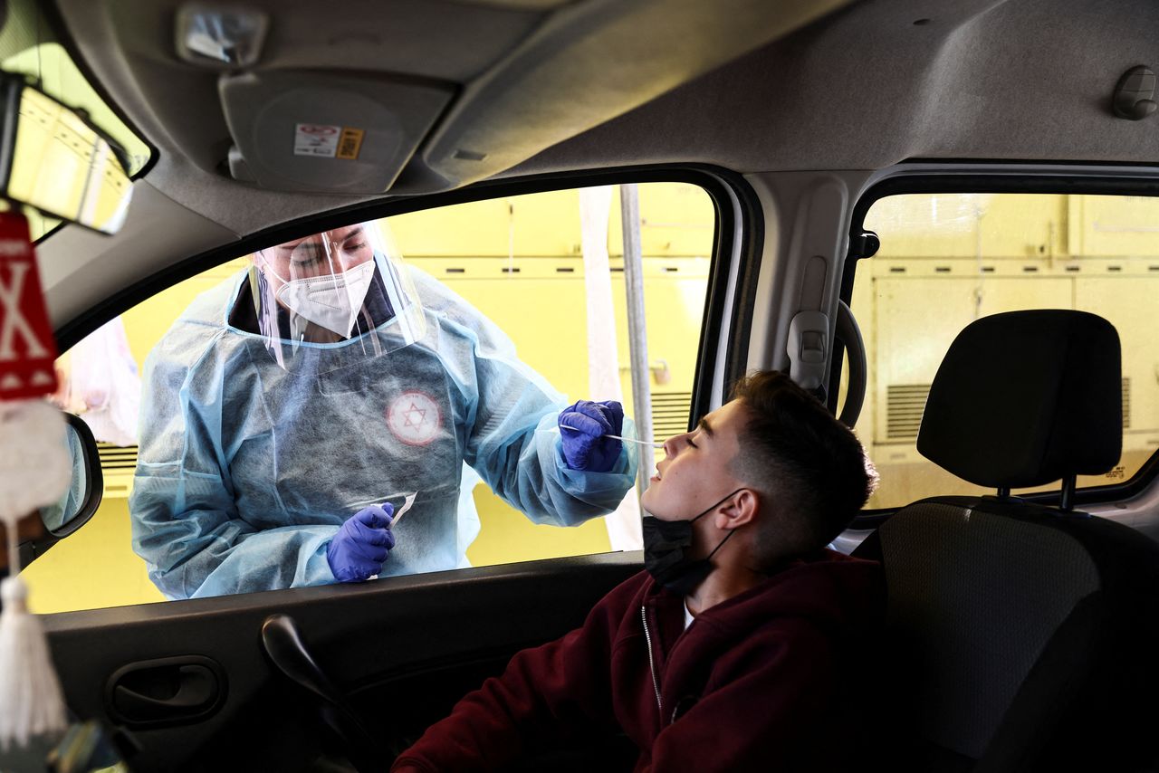 صبي أثناء فحصه للكشف عن فيروس كورونا في سيارته في القدس يوم الاثنين مع تزايد اعداد المصابين بسلالة أوميكرون في اسرائيل. تصوير:رويترز.