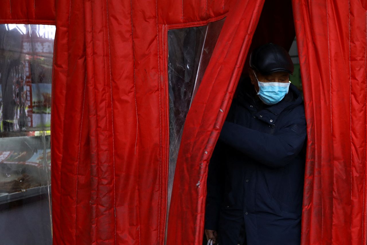 رجل يضع كمامة للوقاية من الإصابة بفيروس كورونا يخرج من سوق في العاصمة الصينية بكين يوم الجمعة. تصوير: تينغشو وانغ - رويترز.