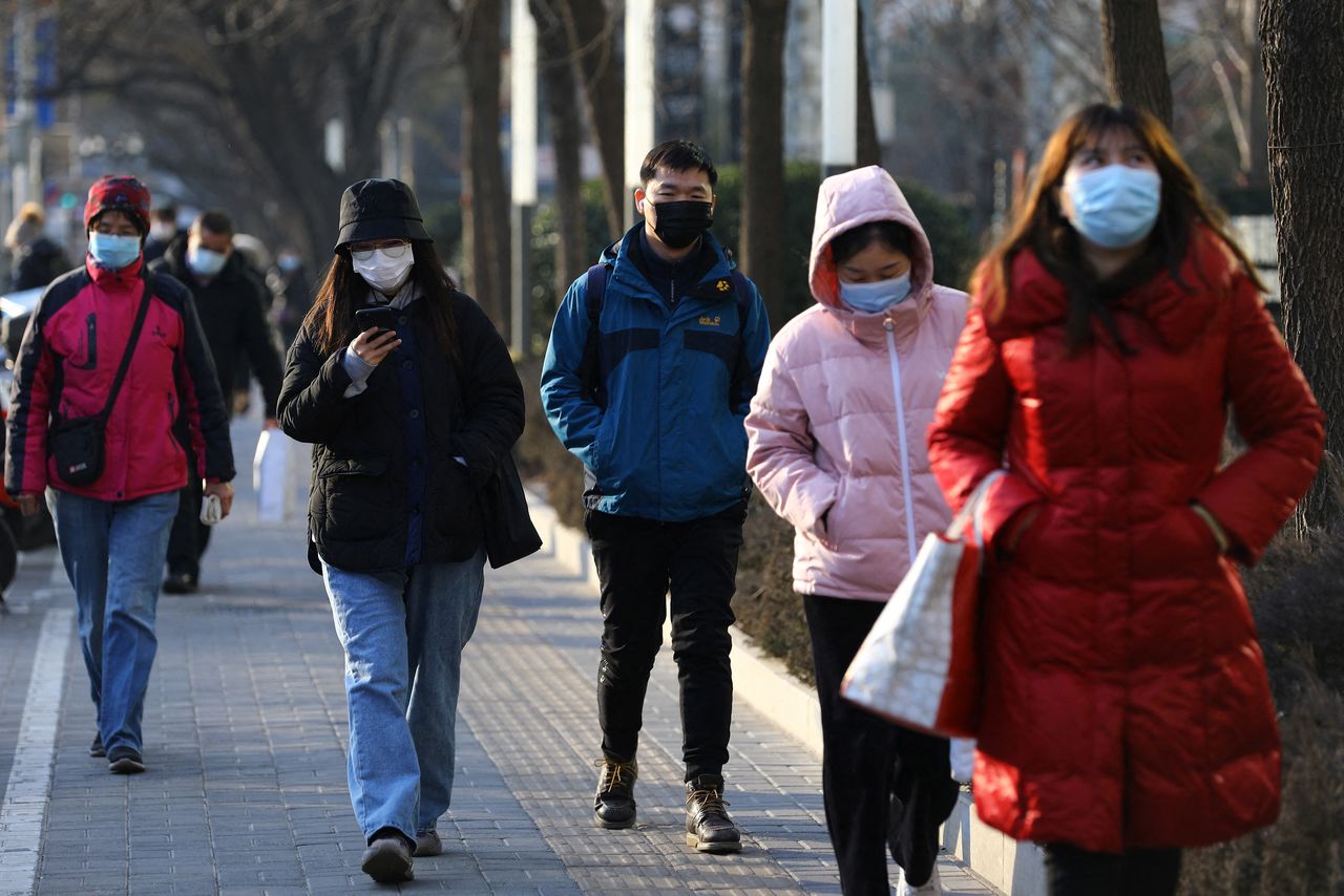 مارة يتبعون إجراءات الوقاية من فيروس كورونا في أحد شوارع بكين يوم 18 يناير كانون الثاني 2022. رويترز