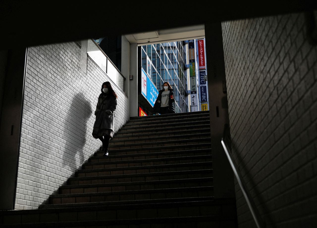 أشخاص يرتدون أقنعة واقية يسيرون في الشارع وسط جائحة فيروس كورونا، في طوكيو، اليابان، 19 يناير/ كانون الثاني 2022. رويترز / إيسى كاتو.