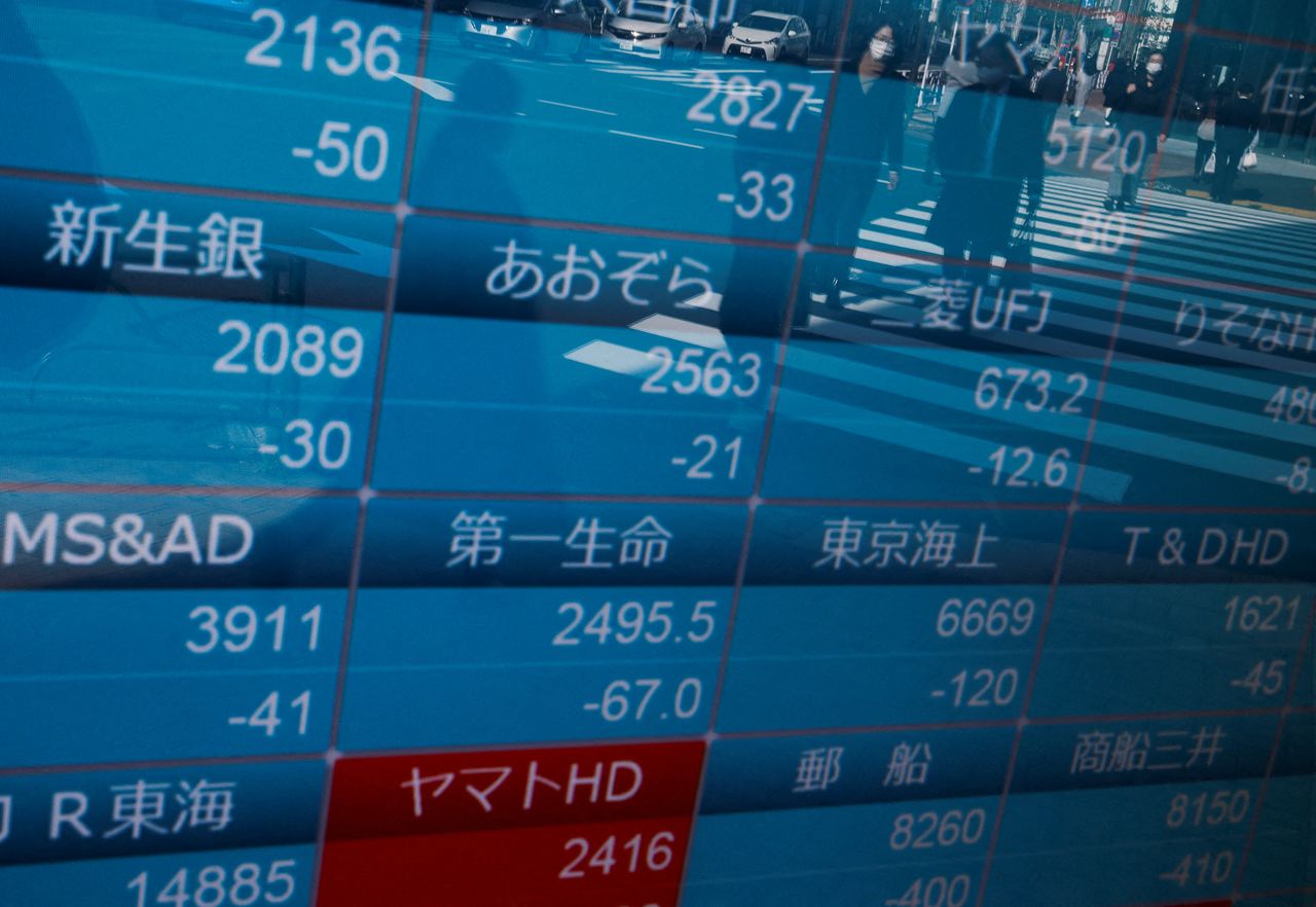 انعكاس مارة يضعون كمامات للوقاية من فيروس كورونا على لوحة تعرض تحركات الأسهم في طوكيو يوم الثلاثاء. تصوير: إيسي كاتو - رويترز.