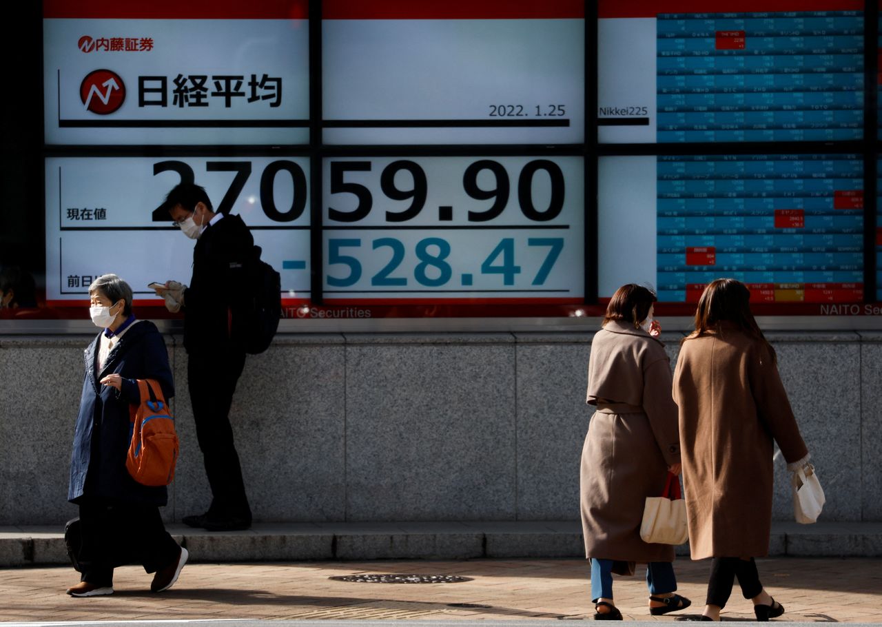 مجموعة من المارة يرتدون كمامات ويمرون أمام لوحة تعرض لأسعار الأسهم المتداولة في بورصة طوكيو يوم 25 يناير كانون الثاني 2022. تصوير:رويترز.
