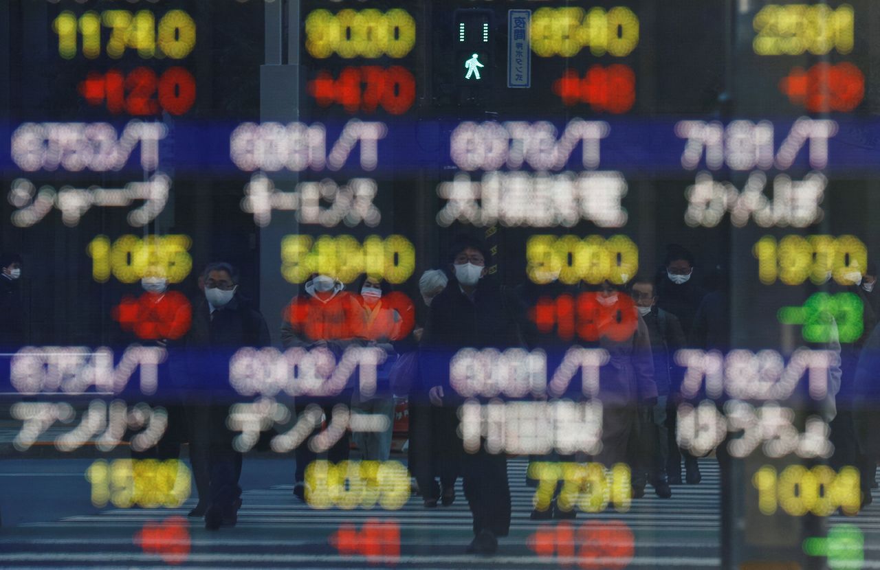 مجموعة من المارة يرتدون الكمامة ويمرون أمام لوحة الكترونية تظهر أسعار الأسهم خارج مكتب للسمسرة في طوكيو يوم 25 فبراير شباط 2022. تصوير:كيم كيونج هوون-رويترز.