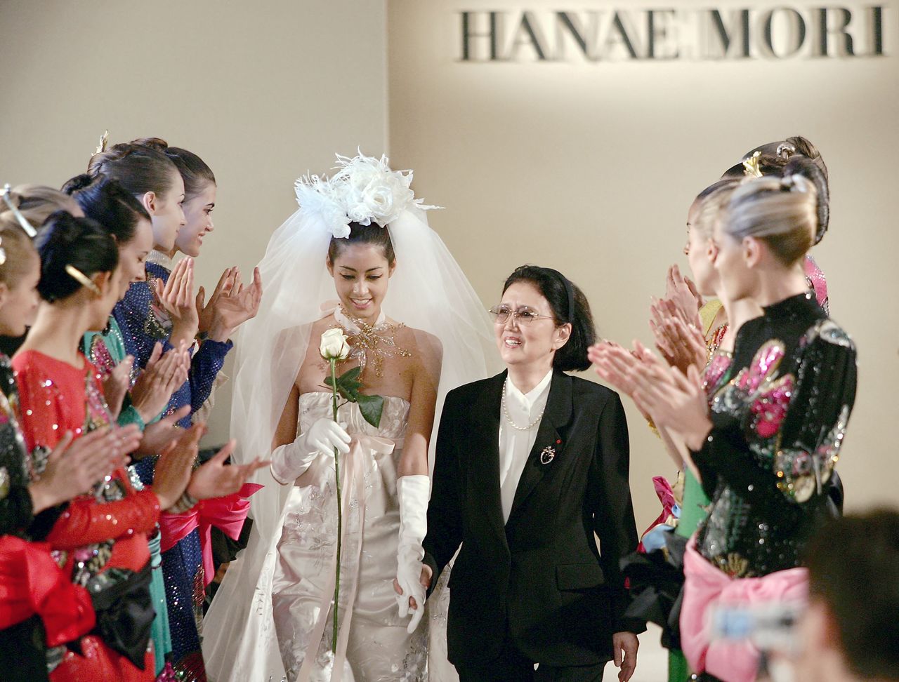     Mori Hana (center right) holds the hand of her granddaughter Mori Izumi at a show of her fall/winter haute couture collection in Paris on July 7, 2004. (Gigi Press)
