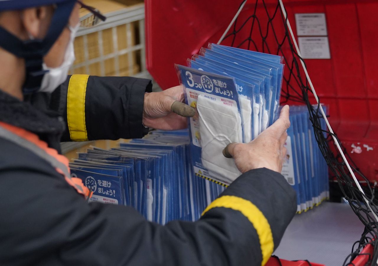 أحد موظفي مكتب البريد يحزم بعضًا من الكمامات لإرسالها إلى مختلف الأسر اليابانية عبر خدمات التوصيل بالدراجات النارية في حي (سيتاغايا)، بطوكيو، في السابع عشر من أبريل/ نيسان. جيجي برس.