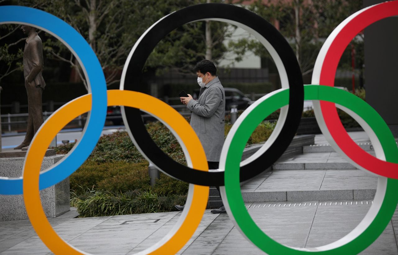 جل ينظر إلى هاتفه المحمول بجوار الحلقات الأولمبية أمام متحف الألعاب الأولمبية اليابانية في طوكيو، اليابان، 4 مارس/ آذار 2020. رويترز / ستويان نينوف.