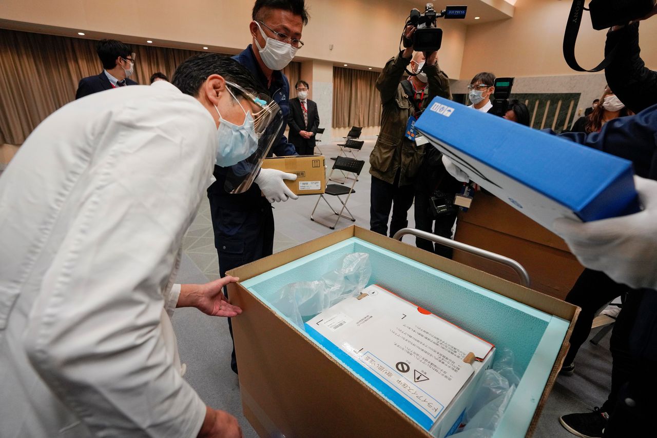 أحد موظفي مستشفى طوكيو يتحقق من درجة حرارة لقاح كورونا من شركة فايزر مع موظفي التوصيل في مستشفى في طوكيو، اليابان، 16 فبراير/ شباط 2021. Kimimasa Mayama / Pool via REUTERS.