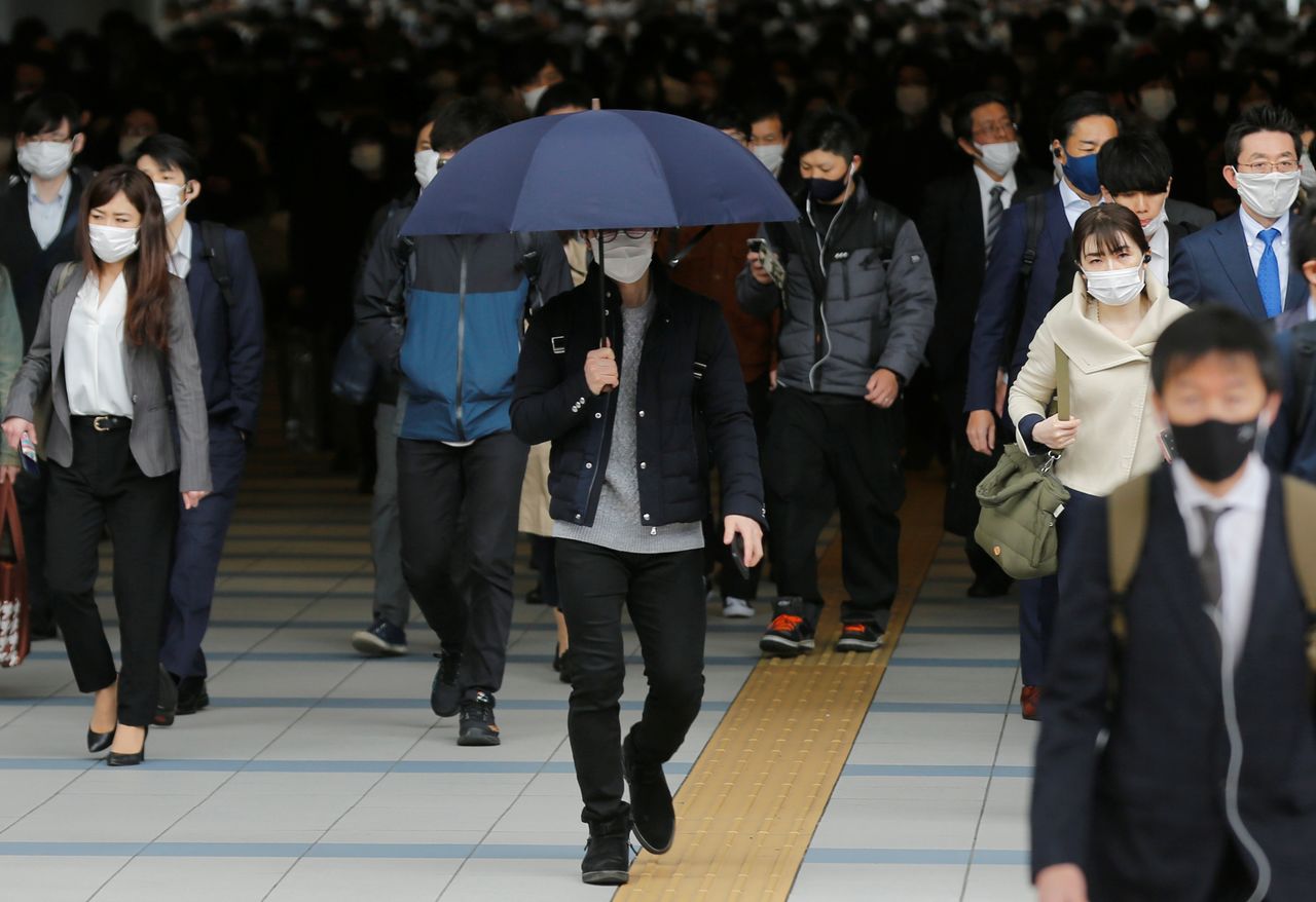 رجل يمشي بمظلة في يوم مشمس بينما يرتدي الناس أقنعة واقية للوجه وسط جائحة فيروس كورونا في طوكيو، اليابان، 6 أبريل/ نيسان 2021. رويترز / كيم كيونغ هون.