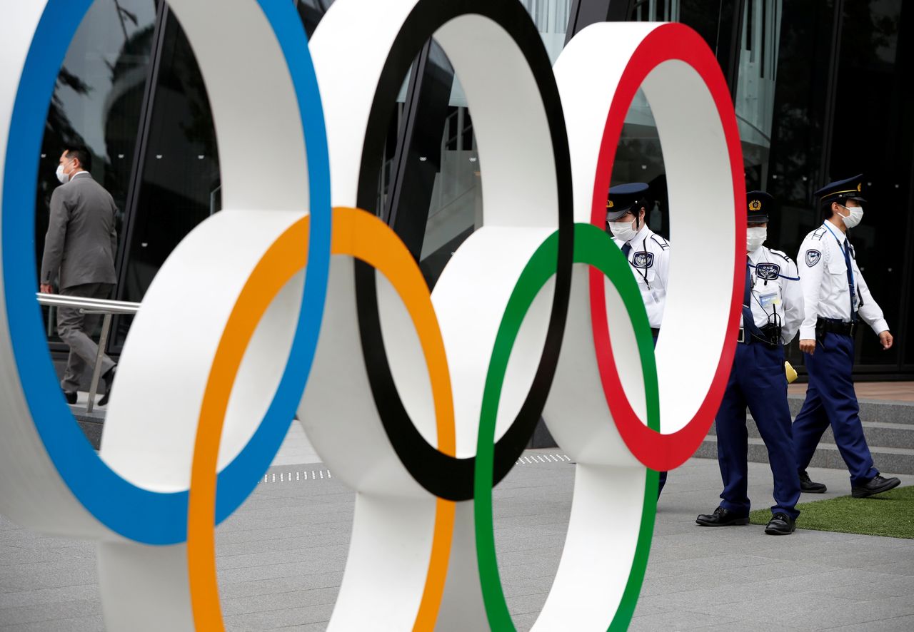 أفراد أمن يقفون بالقرب من نصب الحلقات الأولمبية خلال مسيرة للمتظاهرين المناهضين للأولمبياد خارج مقر اللجنة الأولمبية اليابانية، وسط تفشي فيروس كورونا، في طوكيو، اليابان، 18 مايو/ أيار 2021. رويترز / إيسي كاتو.