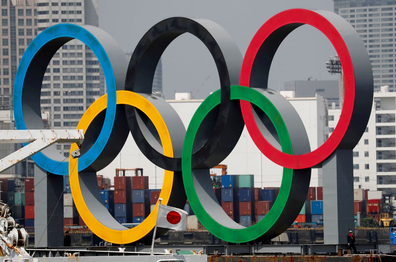 الحلقات الأولمبية العملاقة تظهر خلف العلم الوطني لليابان وسط تفشي مرض فيروس كورونا، في منطقة الواجهة البحرية في حديقة أودايبا البحرية في طوكيو، اليابان، 6 أغسطس/ آب، 2020.