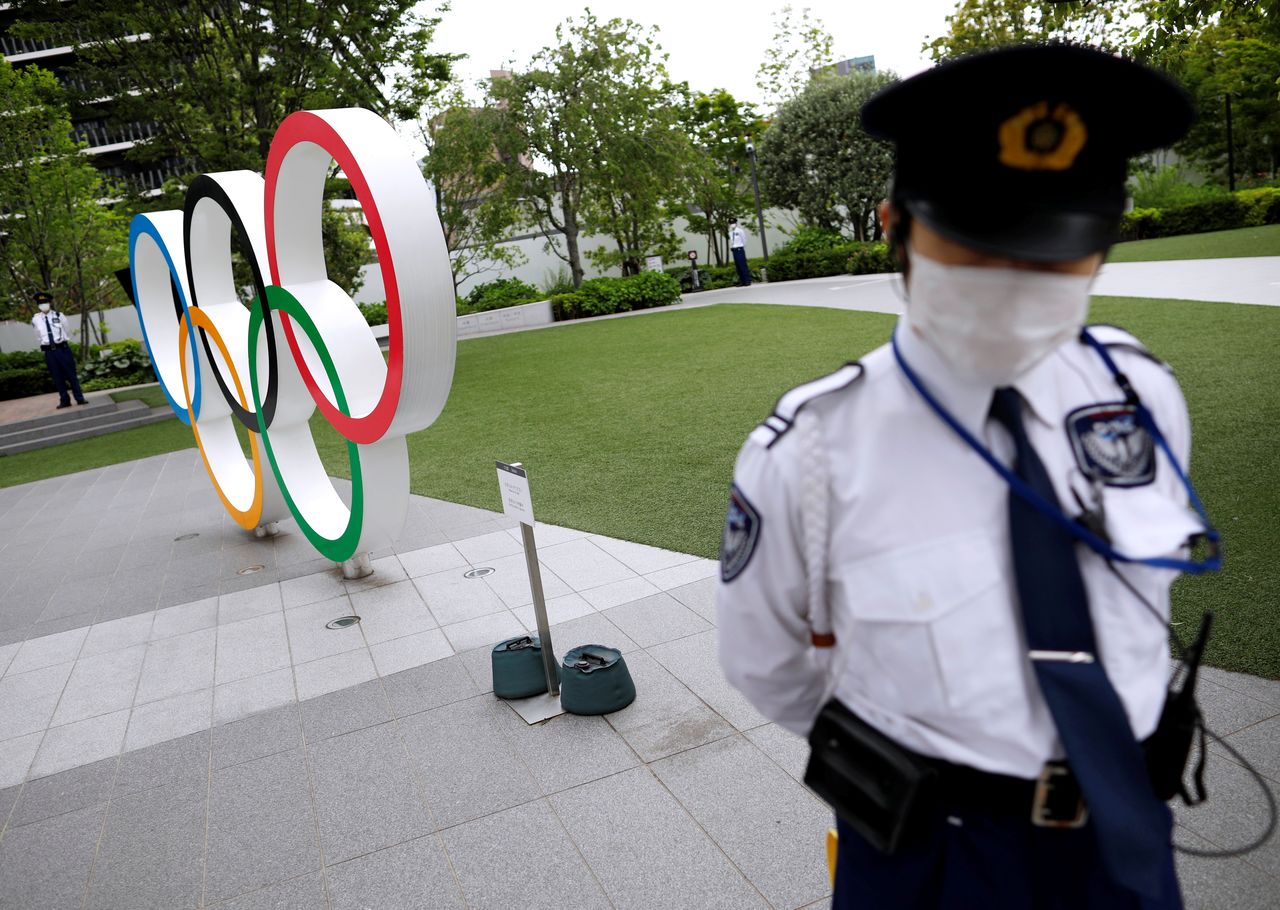 فرد أمن يقف بالقرب من مجسم الحلقات الأولمبية خلال مسيرة للمتظاهرين المناهضين للأولمبياد خارج مقر اللجنة الأولمبية اليابانية، وسط تفشي جائحة فيروس كورونا، في طوكيو، اليابان ، 18 مايو/ أيار 2021. رويترز/ إيسّي كاتو.