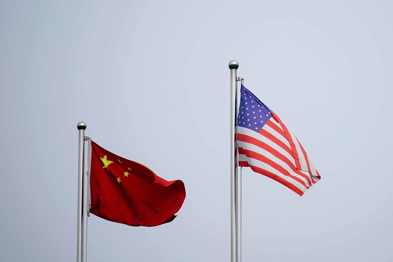 العلمان الأمريكي والصيني يرفرفان خارج مبنى شركة في شنغهاي يوم 14 أبريل نيسان 2021. تصوير: رويترز.