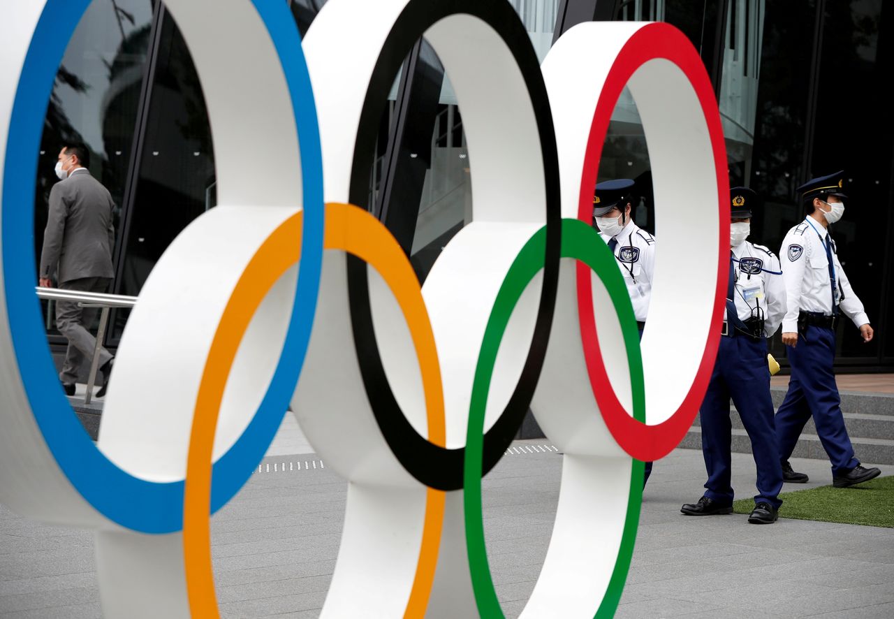 أفراد أمن يقفون بالقرب من نصب الحلقات الأولمبية خلال مسيرة للمتظاهرين المناهضين للأولمبياد خارج مقر اللجنة الأولمبية اليابانية، وسط تفشي فيروس كورونا، في طوكيو، اليابان، 18 مايو/ أيار 2021. رويترز / إيسى كاتو.