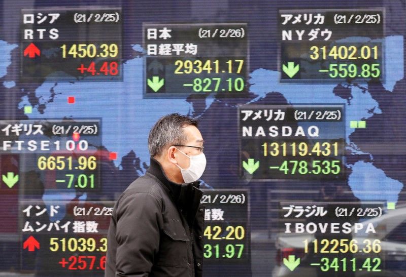 رجل يضع كمامة للوقاية من فيروس كورونا يسير أمام لوحة إلكترونية تعرض مؤشرات الأسواق في طوكيو يوم 26 فبراير شباط 2021. تصوير: كيم كيونج هون - رويترز.