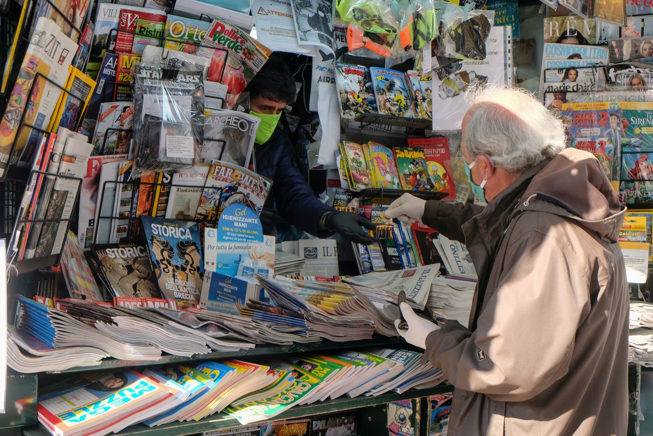 رجل يرتدي كمامة وقفازات أثناء شرائه لجريدة من منفذ لبيع الصحف في البندقية بايطاليا يوم 14 أبريل نيسان 2020. تصوير:رويترز.