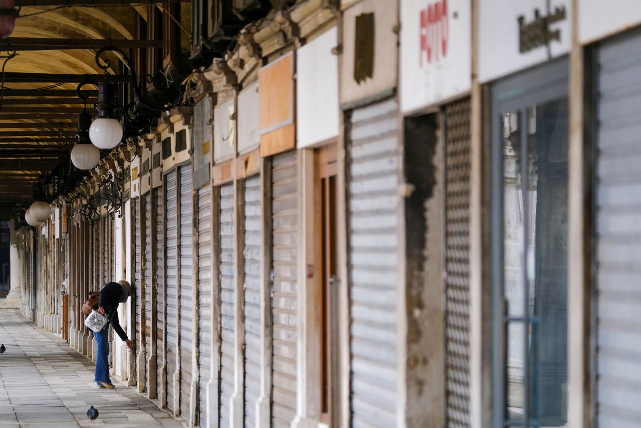 امرأة تغلق متجرا وسط إجراءات للحد من تفشي فيروس كورونا في مدينة البندقية الإيطالية يوم 15 مارس آذار 2021. صورة لرويترز.