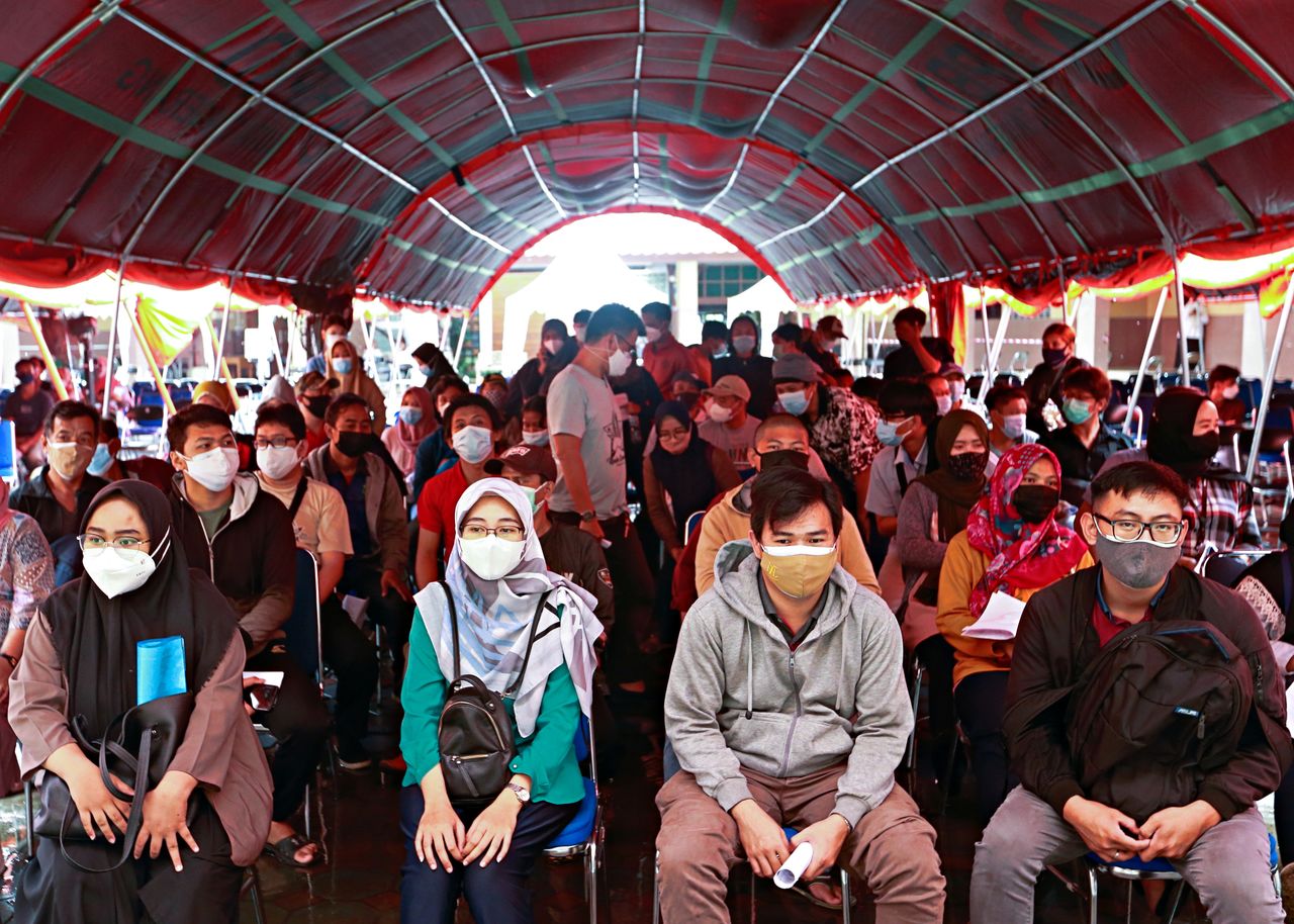 أشخاص يضعون كمامات ينتظرون للحصول على جرعة من لقاح مضاد لفيروس كورونا في جاكرتا بصورة من أرشيف رويترز.