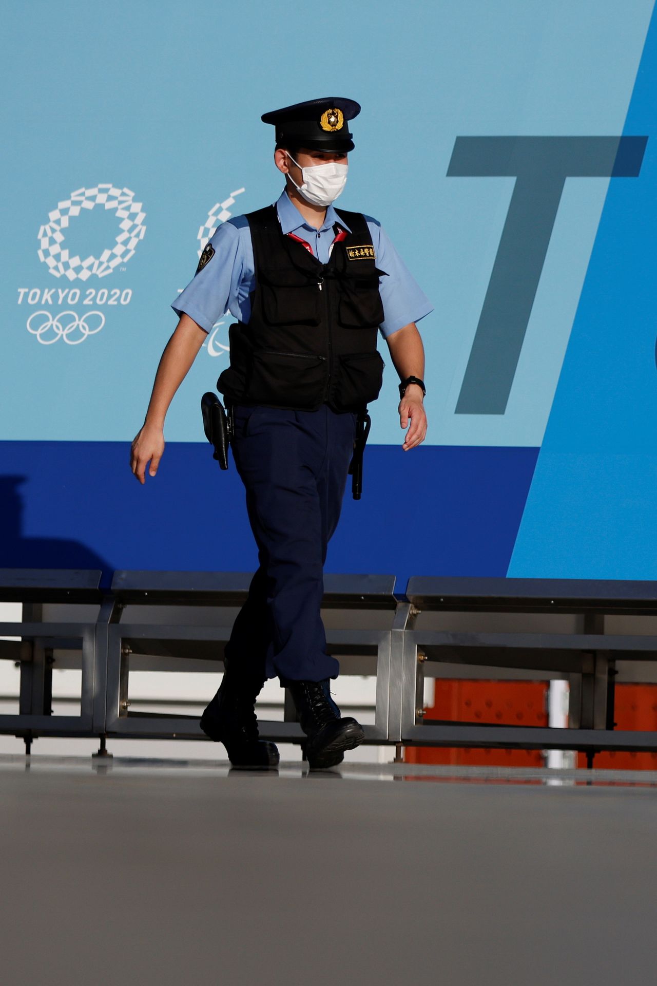 شرطي يضع كمامة للوقاية من فيروس كورونا في طوكيو يوم 16 يوليو تموز 2021. تصوير: توماس بيتر - رويترز.