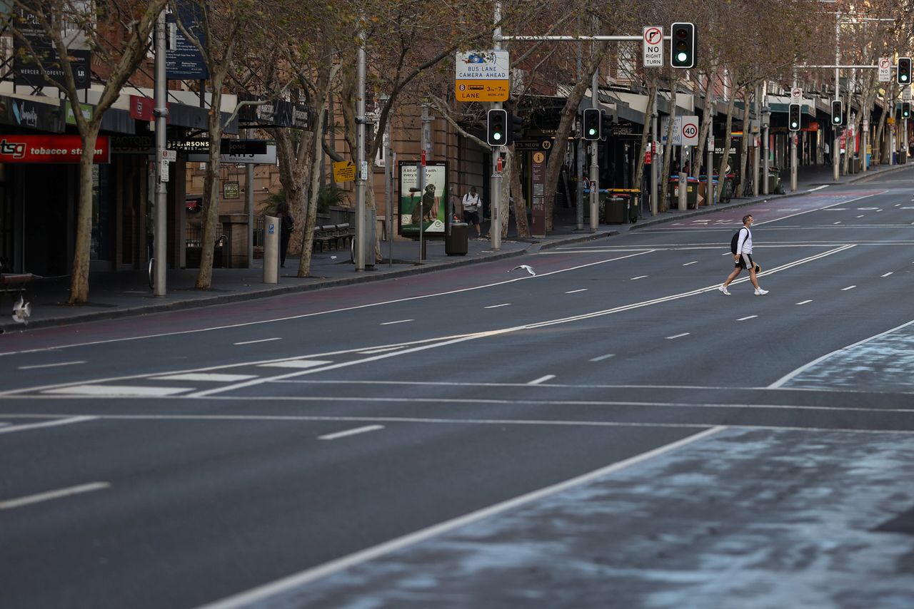 رجل يضع كمامة للوقاية من فيروس كورونا أثناء سيره بأحد شوارع مدينة سيدني الأسترالية يوم الخميس. تصوير: لورين إليوت - رويترز.