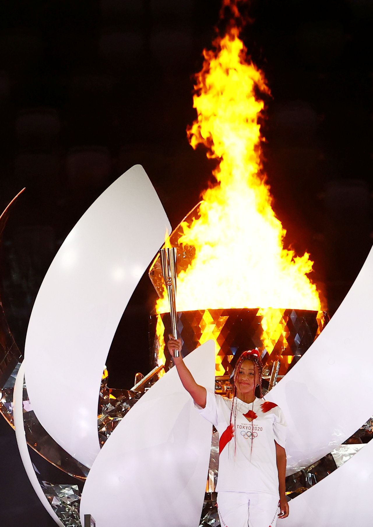 لاعبة التنس اليابانية نعومي أوساكا تحمل الشعلة الأولمبية بعد أن أوقدت المرجل الأولمبي خلال حفل افتتاح أولمبياد طوكيو 2020 يوم الجمعة. تصوير: ستيفان ورموث - رويترز.