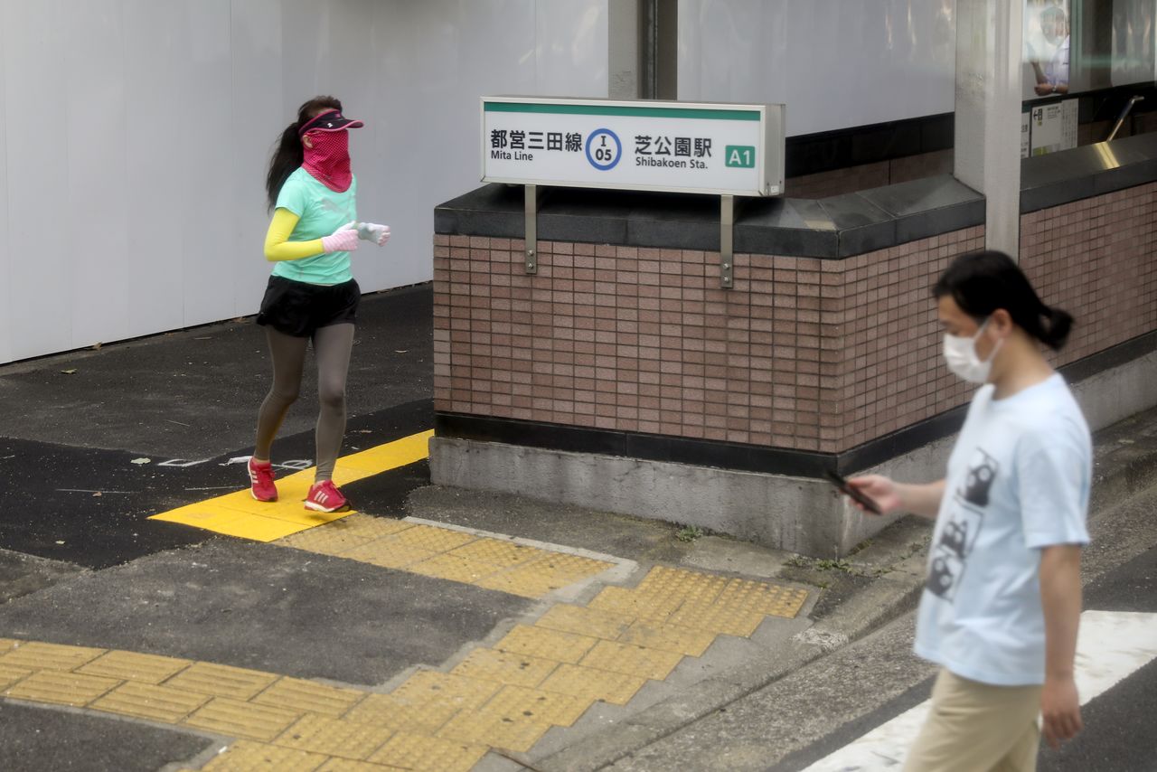 رجل وامرأة يضعان كمامتين بجوار محطة شيباكوين لقطارات الأنفاق خلال جائحة فيروس كورونا في طوكيو يوم الأحد. تصوير: كيفن كومز - رويترز.