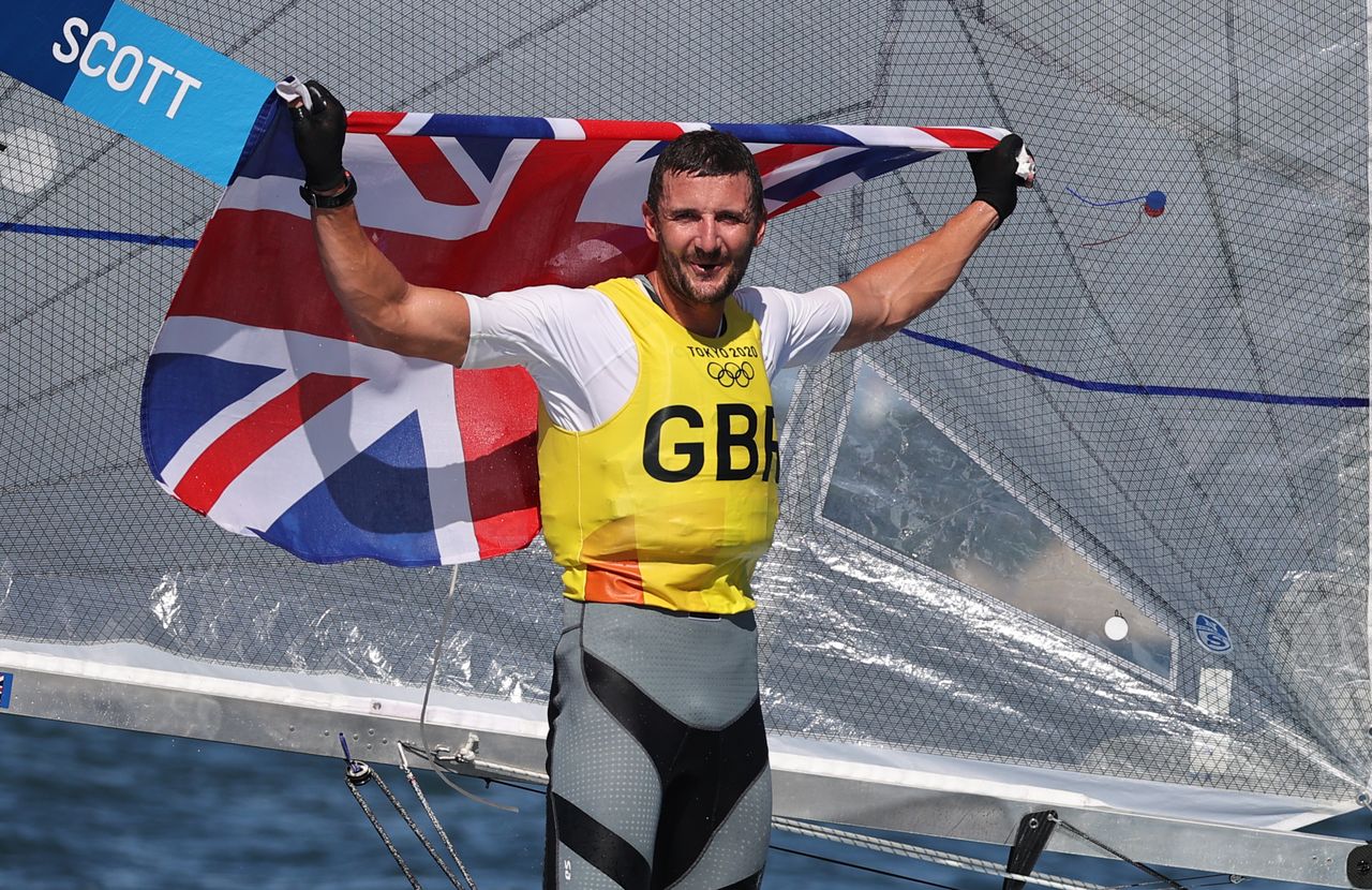 البريطاني جايلز سكوت يرفع علم بلاده بعد الفوز ببذهبية الشراع فئة فين للرجال بأولمبياد طوكيو يوم الثلاثاء. رويترز