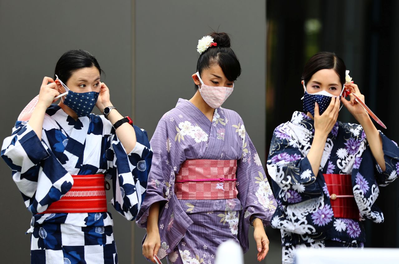 نساء ترتدي الزي التقليدي الياباني وأقنعة واقية يوم الثلاثاء. رويترز