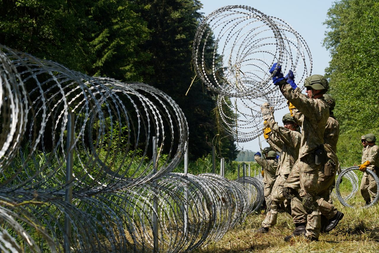 جنود من ليتوانيا يضعون سلكا شائكا على الحدود مع روسيا البيضاء لمنع عبور المهاجرين غير الشرعيين  - صورة من أرشيف رويترز