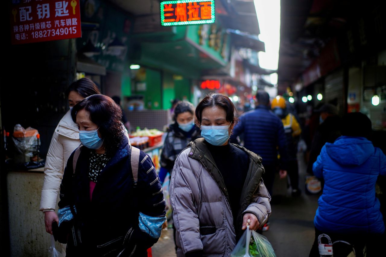 أشخاص يضعون كمامات ويسيرون في شارع تجاري بمدينة ووهان الصينية يوم 8 فبراير شباط 2021. تصوير: رويترز.