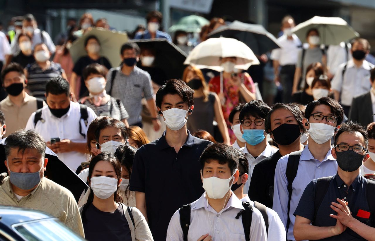 أناس يضعون كمامات لاحتواء تفشي السلالة الجديدة لفيروس كورونا في العاصمة اليابانية طوكيو يوم الجمعة. تصوير: كيم كيونج هون - رويترز.