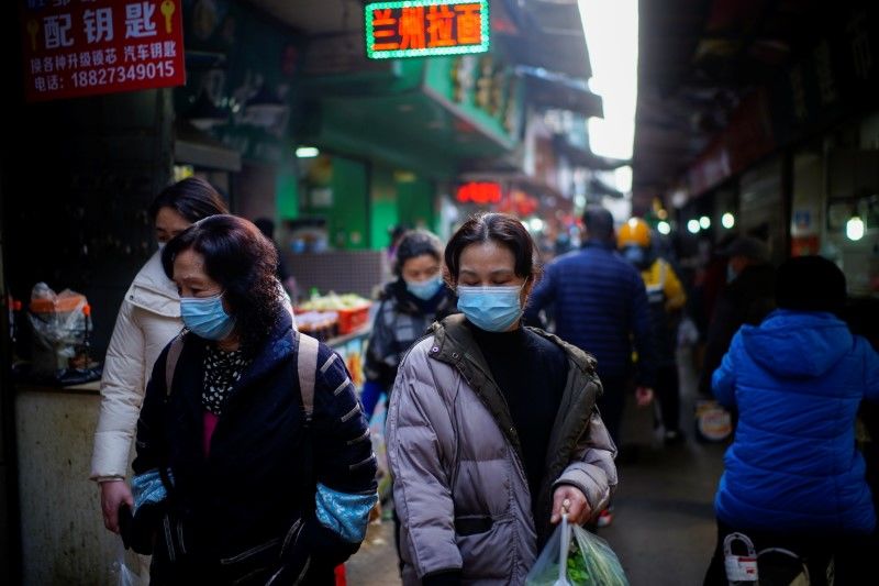 أشخاص يضعون كمامات للوقاية من فيروس كورونا بمدينةووهان الصينية يوم الثامن من فبراير شباط 2021. تصوير: آلي سونغ - رويترز.
