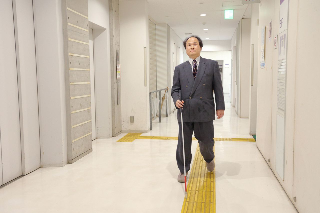 البروفيسور فوكوشيما يسير في رواق مركز أبحاث جامعة طوكيو للعلوم والتكنولوجيا المتقدمة. إنه قادر على استخدام المرحاض دون مساعدة (© هاناي توموكو)