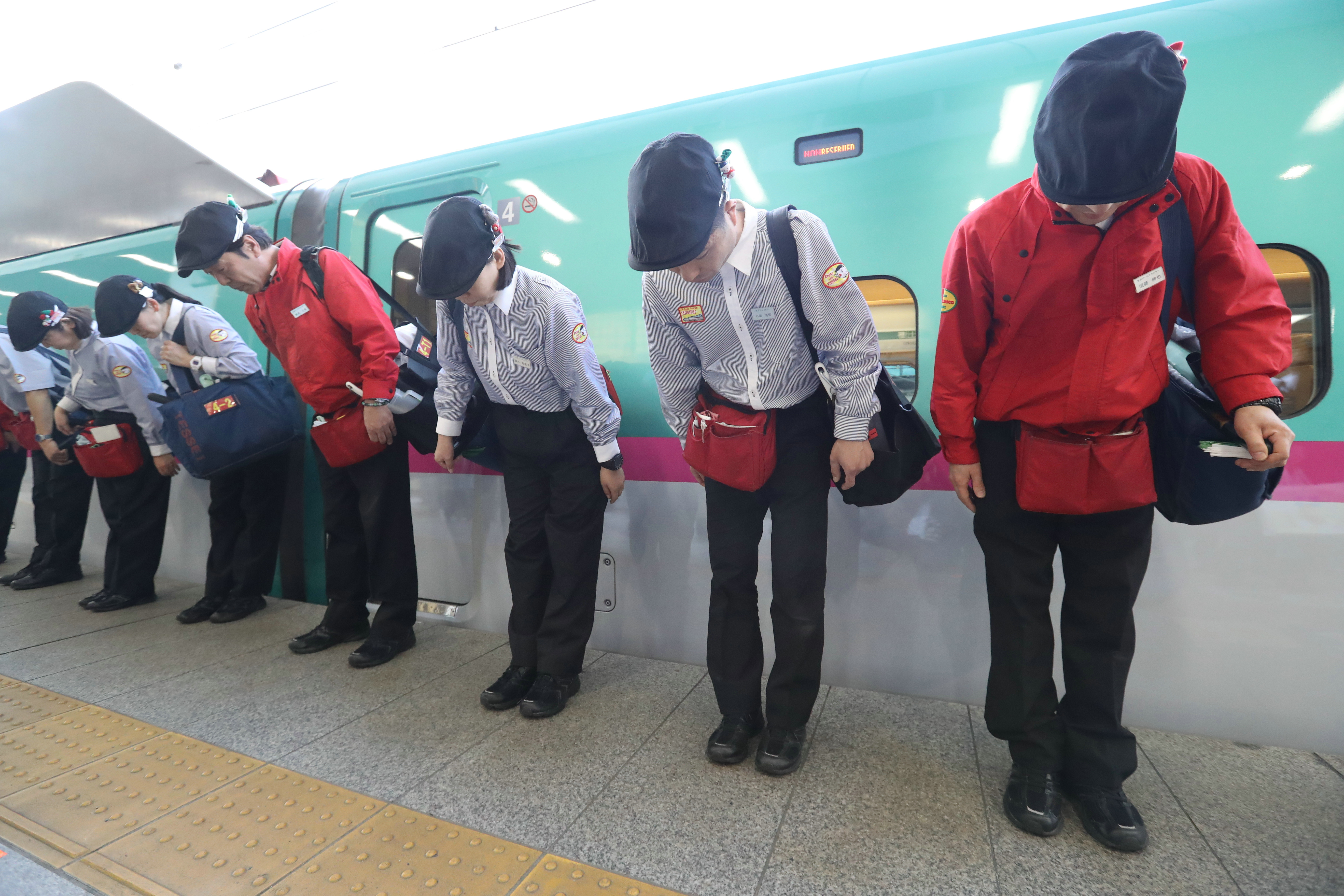完成新干线车厢内的清扫工作后，清扫员在站台上行礼致意。JR东京站（时事社）