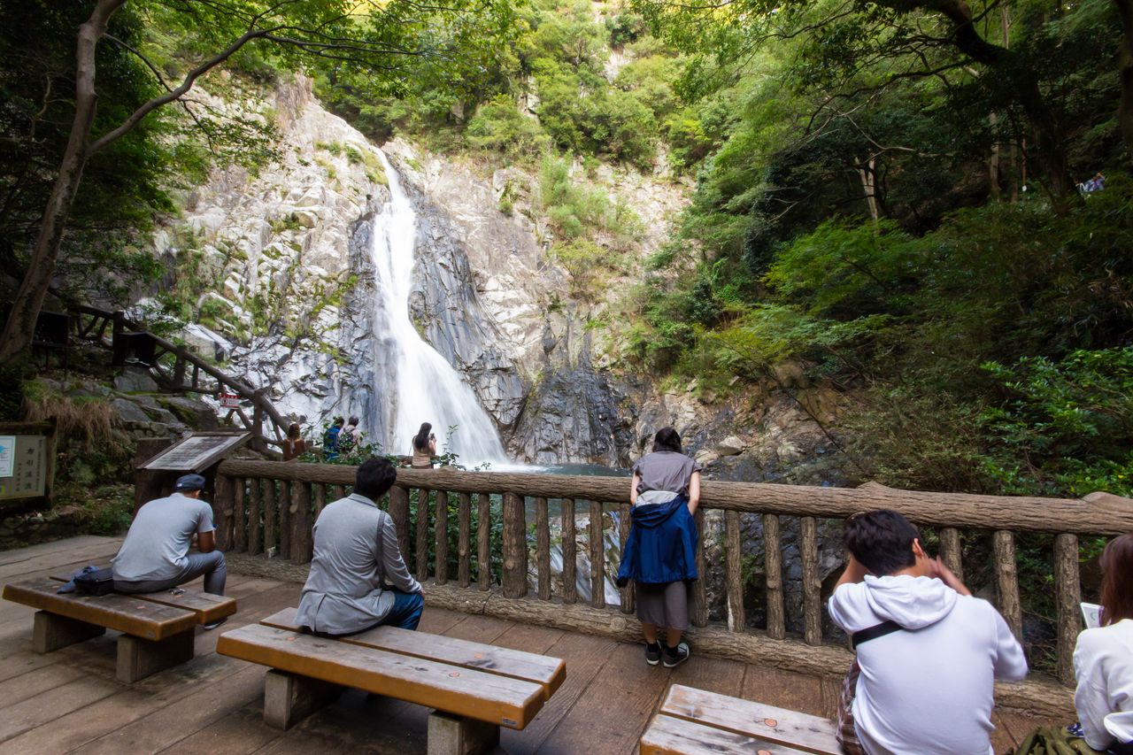 游客们在观赏轰隆作响、水花四溅的雄滝