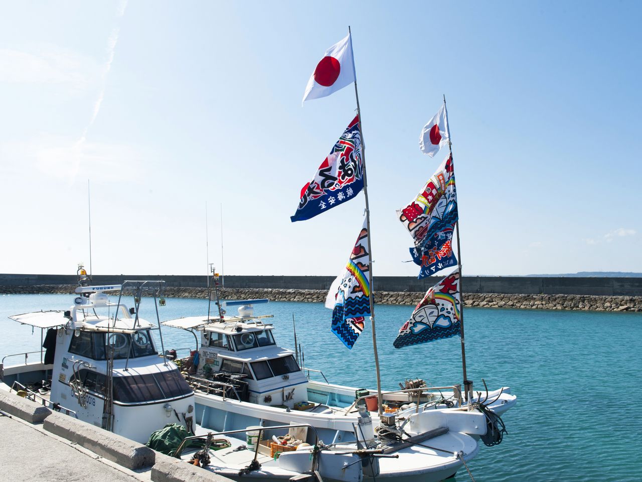 停泊在渔港的船只上挂着祈求丰收的“大渔旗”