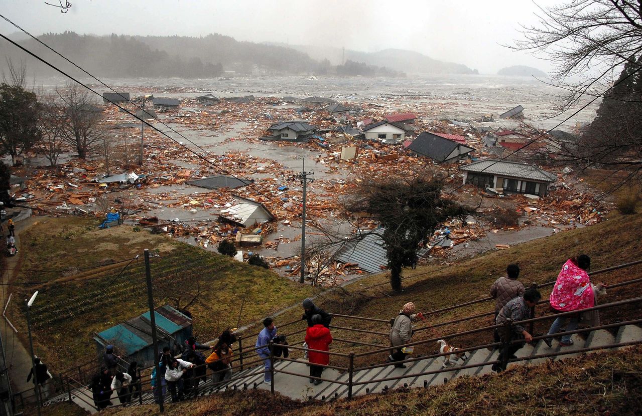 3月11日 下午3时37分 宫城县南三陆町志津川 在高地上避难的居民，茫然地观望着一瞬间面目全非的村景。