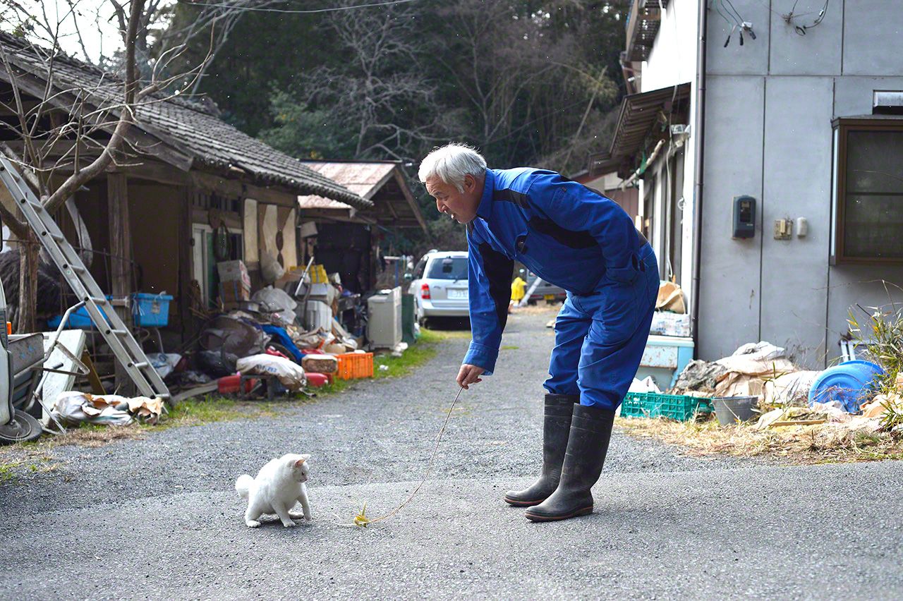 与猫咪一起玩耍的松村先生。时光流过，漫长而悠闲，仿佛这里根本未曾受到污染