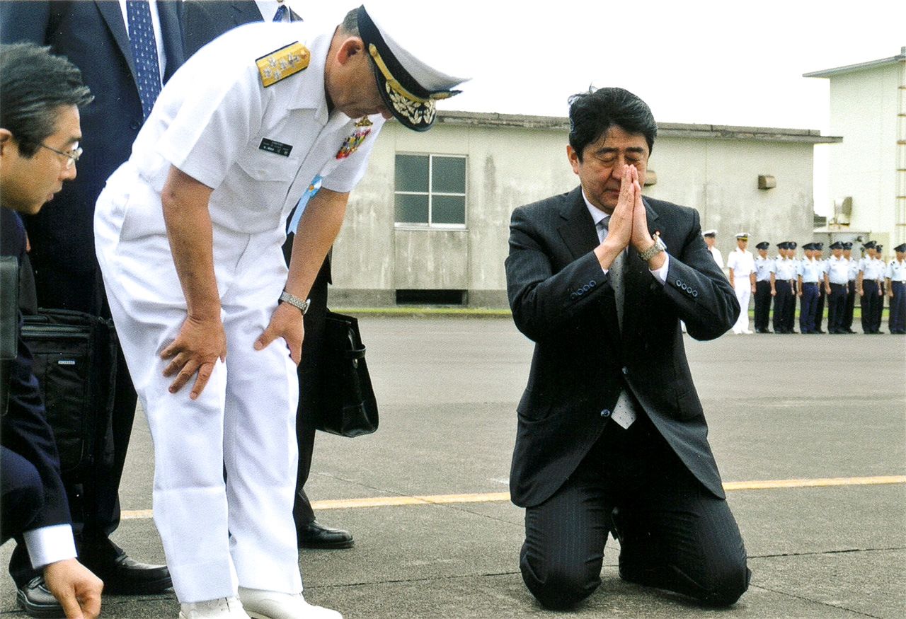 安倍首相（右）视察众多战死日本士兵长眠的硫磺岛，在飞机跑道上突然跪地合掌，海上幕僚长河野克俊（左起第2人）在其身旁（河野提供）