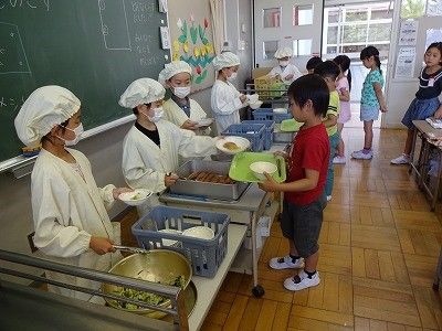 东京都小平市的一所小学的学生正在给同学分发午餐。一到中午时分，日本全国各地的小学都可见到这样的风景