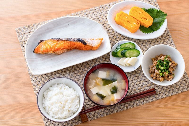 典型的日式早餐（从右下角顺时针依次为：香葱纳豆、豆腐裙带菜味噌汤、米饭、盐腌三文鱼、泡菜、煎蛋卷）