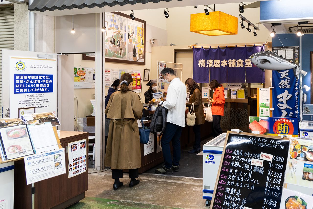 横滨屋本店食堂左手的广告牌引人注目，上面写着“本店提供MEL认证食品”