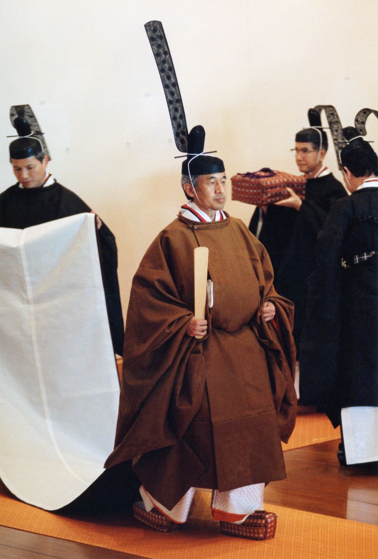 明仁天皇（现在的上皇）在平成时代的“即位礼正殿之仪”中穿着的黄栌染御袍。上有桐、竹、凤凰、麒麟的纹饰。天皇右手执笏板，脚踏名为“插鞋”的木履，表面贴有锦布，造型类似于神职人员穿着的“浅沓”。1990年11月12日，皇居宫殿“松之间”[记者团代表摄影]（时事社） 