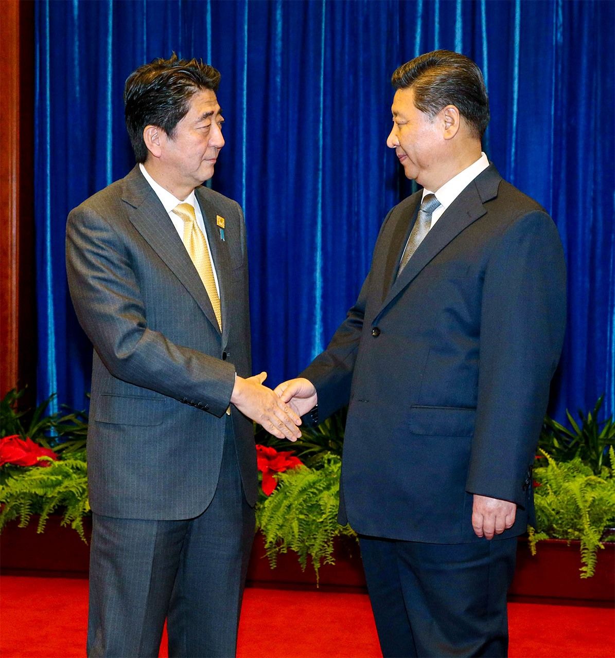 在日中首脑会谈前，习近平主席（右）与安倍晋三首相握手（2014年11月10日于北京人民大会堂，时事社，记者团代表摄影）