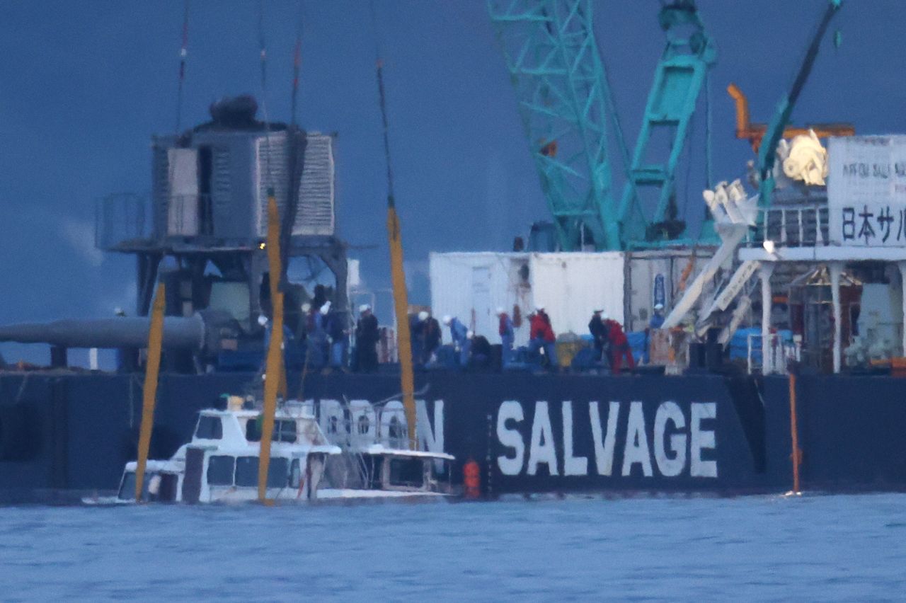 被作业船“海进”(打捞公司“日本Salvage”)打捞,浮出海面的游船“KAZU I”(左下)(2022年5月,北海道斜里町)(图片:时事社)