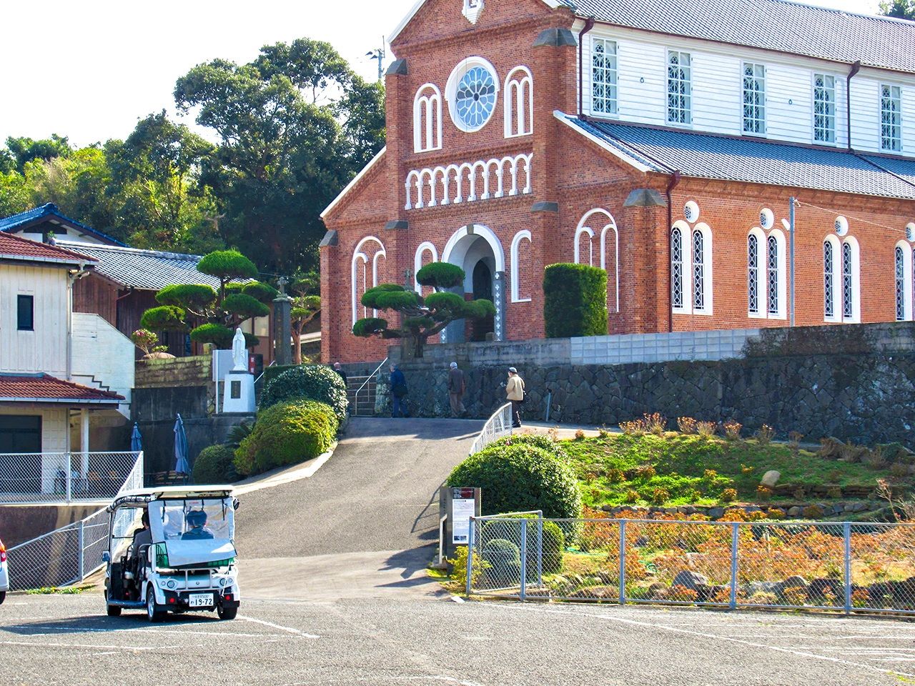 行驶在日本重要文化遗产“黑岛天主堂”前的4座新能源低速电动车。在这座没有公共交通的小岛上，这种电动车不仅服务于观光，将来还有望成为当地居民的代步工具（图片：黑岛观光协会）