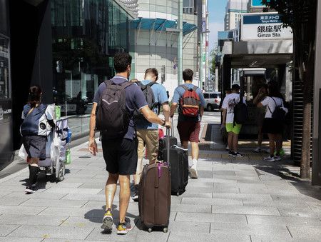 拉着行李箱走在东京银座街道上的外国游客，7月10日，东京都中央区