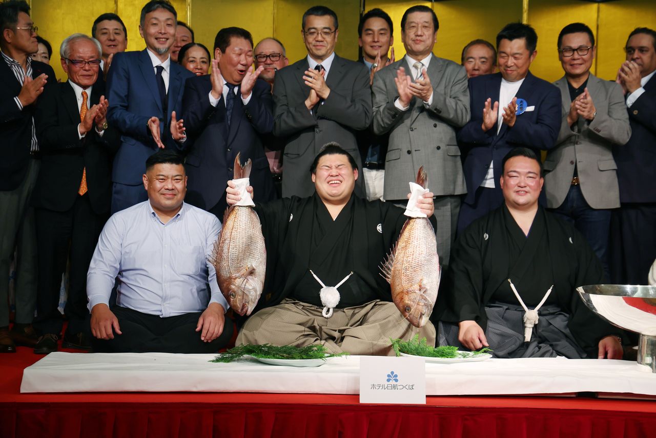 大之里夺得夏季赛事冠军,手举鲷鱼庆祝。右边是师傅、原横纲稀势之里。茨城县筑波市(时事社)