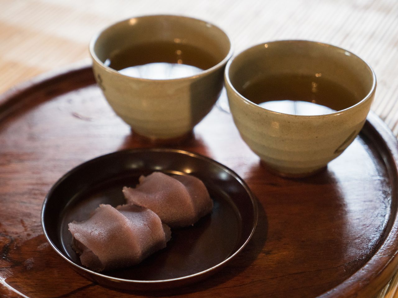 Akafuku <em>mochi</em> rice cakes, wrapped in koshi-an bean jam. Here the mochi are served with cups of <em>bancha</em> (coarse Japanese tea), for eating on the premises.
