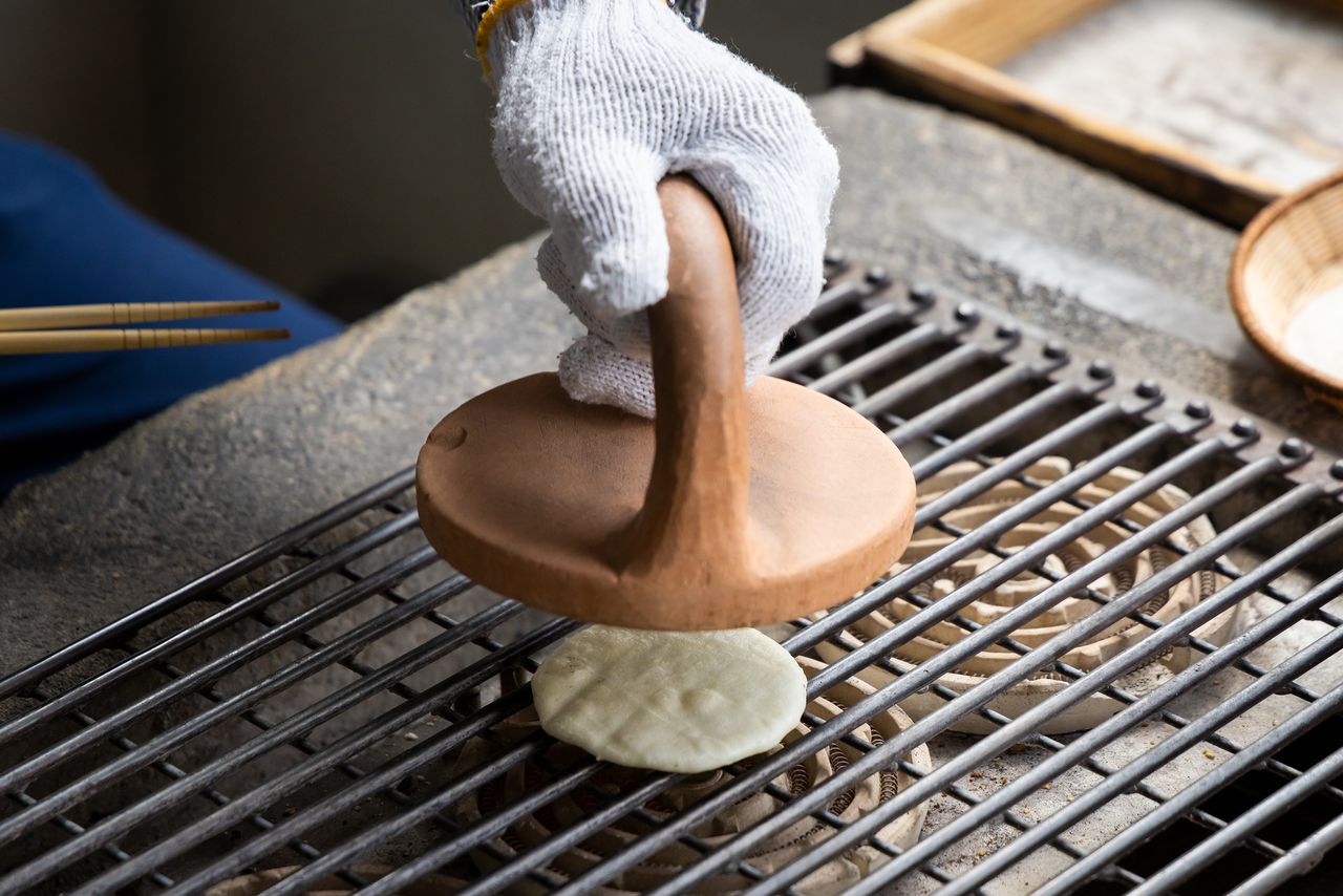Applying the weighty ceramic oshigawara while the senbei is still soft keeps the cracker flat.