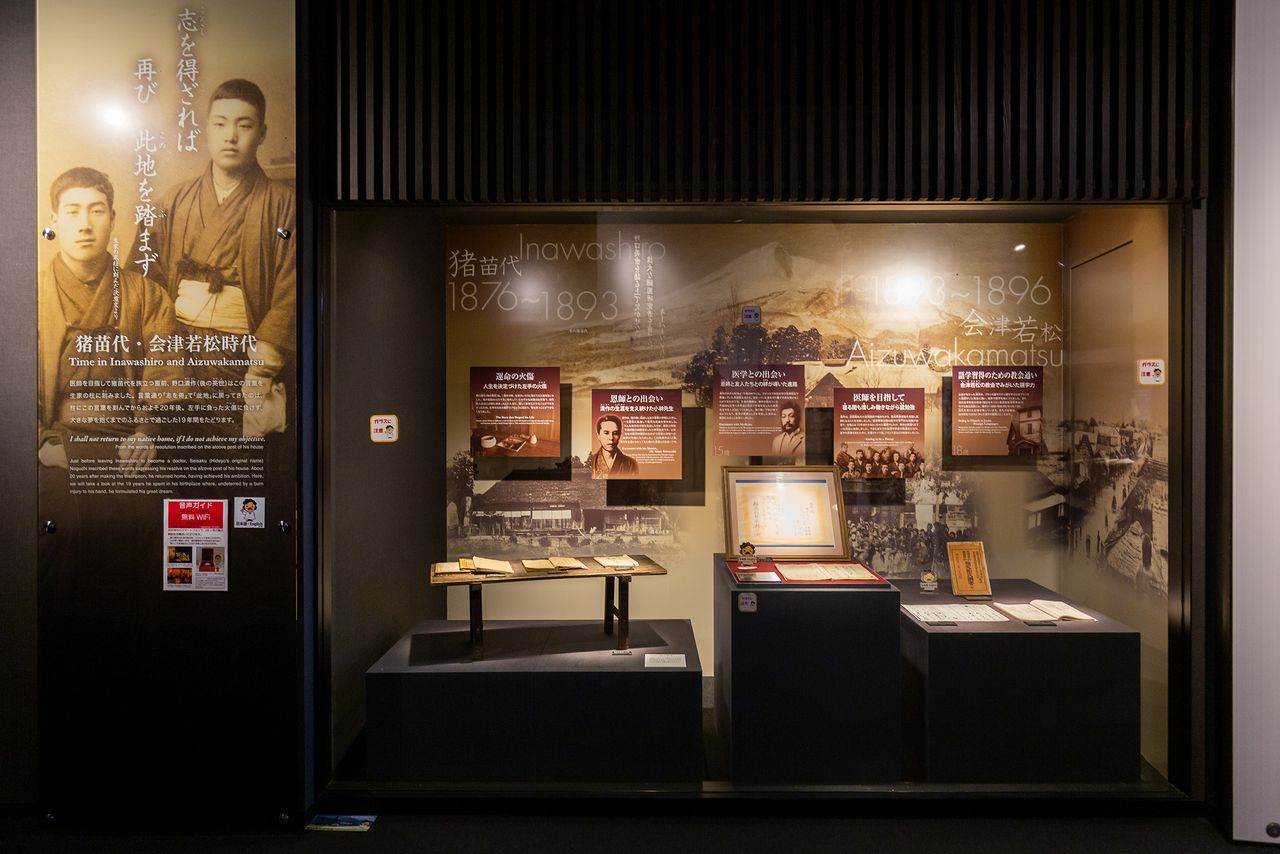 A museum display detailing Noguchi’s time in Inawashiro and Aizu-Wakamatsu. The large photo at left, the first ever taken of Noguchi, shows him standing at right, his hand swaddled in post-operation linen, along with his friend Yago Yasuhei.